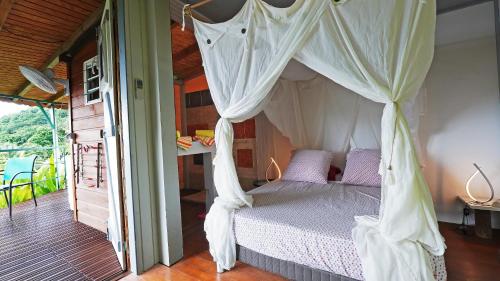 a bedroom with a canopy bed and a balcony at KAZ AMOUR in Bouillante