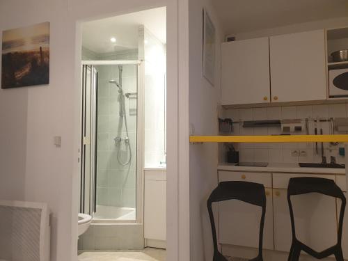 ein Badezimmer mit einer Dusche und zwei schwarzen Stühlen in der Unterkunft studio Vue mer au cœur de malo les bains pieds dans l eau in Dunkerque