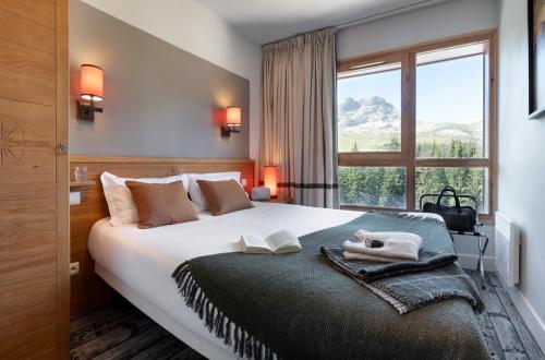 a bedroom with a large white bed with a window at Résidence Pierre & Vacances Premium Les Terrasses d'Eos in Flaine