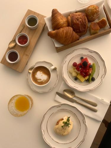 a table with plates of food and cups of coffee and croissants at Hotel Tayko Sevilla in Seville