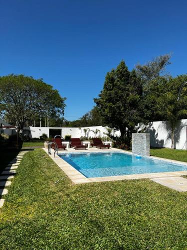 einen Pool in einem Garten mit Bänken und Bäumen in der Unterkunft Hermosa quinta para disfrutar del lugar in Laguna Brava