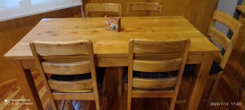 a wooden table with four chairs and a box on it at Cabaña y Domo Rinconada de Malalcahuello in Malalcahuello