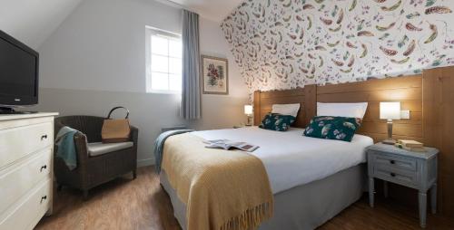- une chambre avec un lit, une télévision et une chaise dans l'établissement Pierre & Vacances Premium Residence & Spa Houlgate, à Houlgate