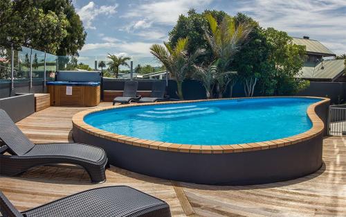 a large swimming pool on a deck with chairs around it at Esplanade Apartments in Whitianga