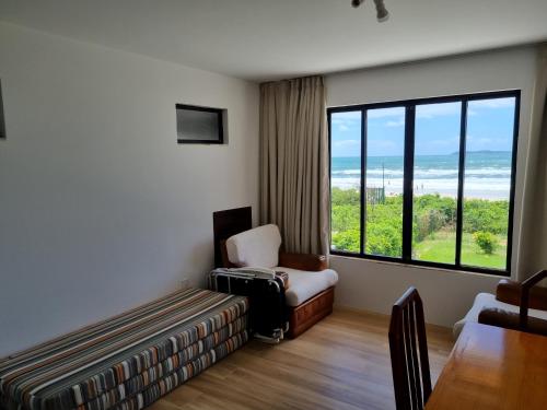 a room with a couch and a chair and a window at Residencial Suites Mariscal in Bombinhas
