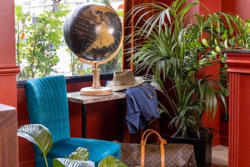 a globe and a chair in a room with plants at Hotel Le Rocroy in Paris