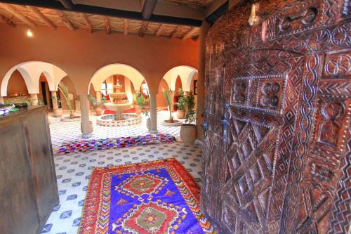 a large wooden door in a room with a rug at Riad Tamdakhte in Aït Ben Haddou