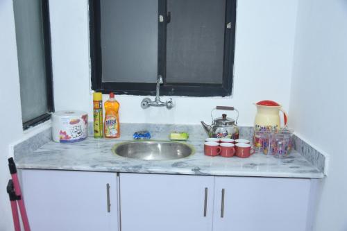 a kitchen counter top with a sink and some dishes at HYATT ARYANA Guesthouse 1 in Islamabad