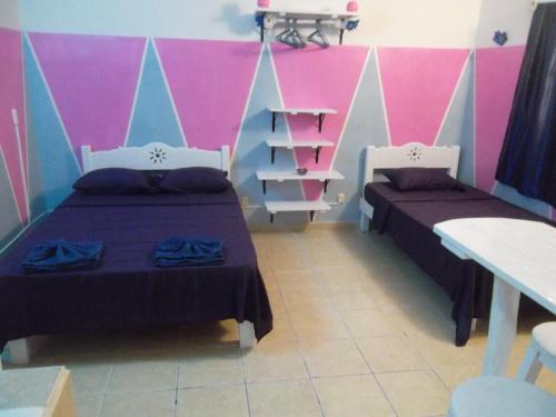 2 camas en una habitación con paredes rosas y azules en Appartamenti Melissa, en Playa del Carmen