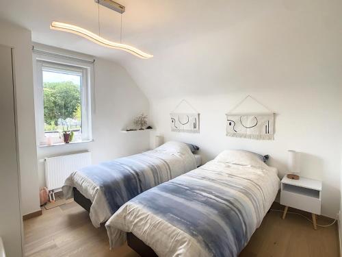 two beds in a white room with a window at Maison 2 ch avec Piscine intérieure et Spa privatif in Floreffe