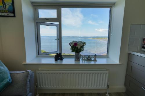 a window with a vase of flowers on a table at The Gaslight Inn Self Catering Holiday Apartments Rossnowlagh Donegal in Rossnowlagh