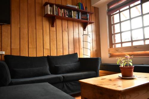 a living room with a black couch and a coffee table at Cinerama Hostel in San Carlos de Bariloche