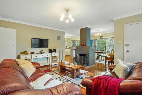 a living room with two leather couches and a fireplace at Kohi Family Home With Netflix l Gardens View in Auckland