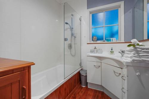 a white bathroom with a shower and a sink at Kohi Family Home With Netflix l Gardens View in Auckland
