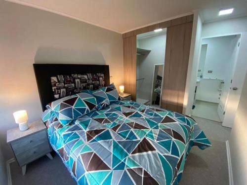 um quarto com uma cama grande e um edredão colorido em Bellísimo y centrico apartamento en La Serena em La Serena