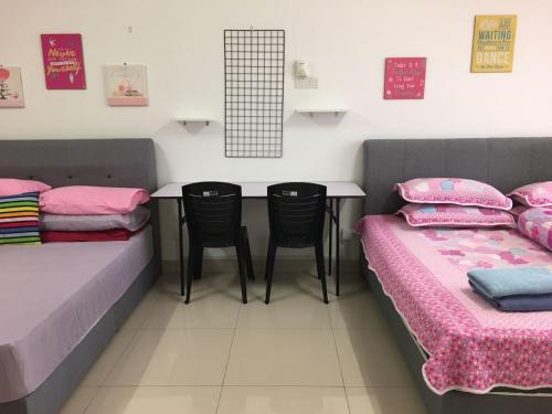 a room with two beds and a table and chairs at Azin Ramli Studio in Seri Kembangan