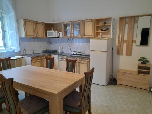 eine Küche mit einem Holztisch und einem weißen Kühlschrank in der Unterkunft Főtér Apartman Baja in Baja