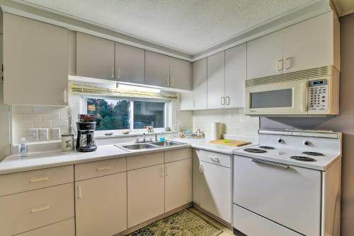 a kitchen with white cabinets and a sink and a microwave at East Tawas Cabin with Lake Huron Access and Views in East Tawas