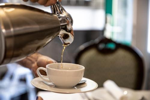 een persoon die koffie in een kopje op een tafel giet bij Quinta da Saraiva in Câmara de Lobos