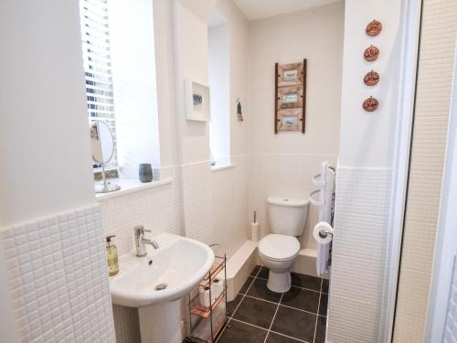 a white bathroom with a sink and a toilet at 3 Coram Tower in Lyme Regis