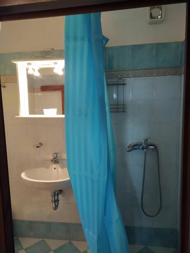 baño con ducha con lavabo y cortina azul en Kouros House - Zen Philosophy, en Palaikastro