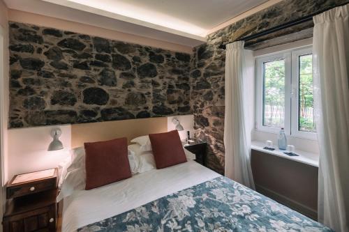 a bedroom with a bed and a stone wall at Quinta da Saraiva in Câmara de Lobos