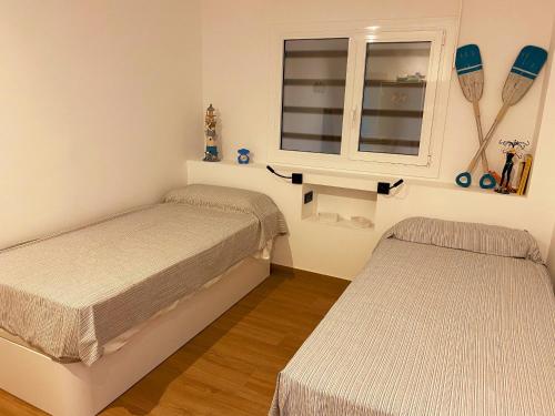 サン・アントニオ・デ・カランジャにあるCozy Flat over the Beach!のベッド2台と窓が備わる小さな客室です。