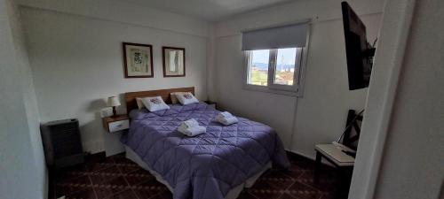 sypialnia z fioletowym łóżkiem i oknem w obiekcie Departamento Ushuaia 2 dormitorios w mieście Ushuaia