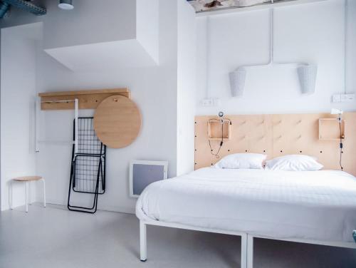 a bedroom with a white bed and a wooden headboard at Ecla Paris Noisy-le-Grand in Noisy-le-Grand