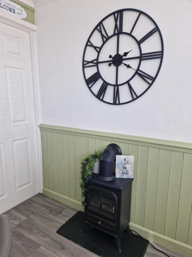a clock on the wall above a stove in a room at Chalet Ty Lilli Wen sleep 6 in Kidwelly
