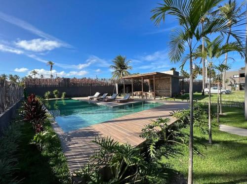 a swimming pool with lounge chairs and palm trees at Praia do Patacho - Milagres in Pôrto de Pedras