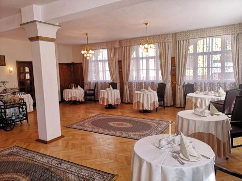 ein Esszimmer mit weißen Tischen, Stühlen und Fenstern in der Unterkunft Hotel Adler in Sankt Georgen im Schwarzwald