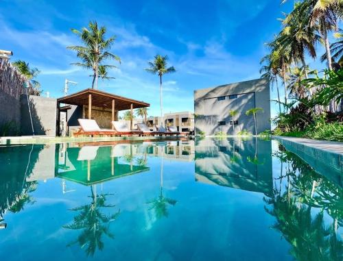 a swimming pool with blue water and palm trees at Praia do Patacho - Milagres in Pôrto de Pedras