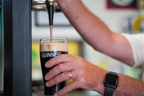 a person is holding a glass of beer at The Gaslight Inn Self Catering Holiday Apartments Rossnowlagh Donegal in Rossnowlagh