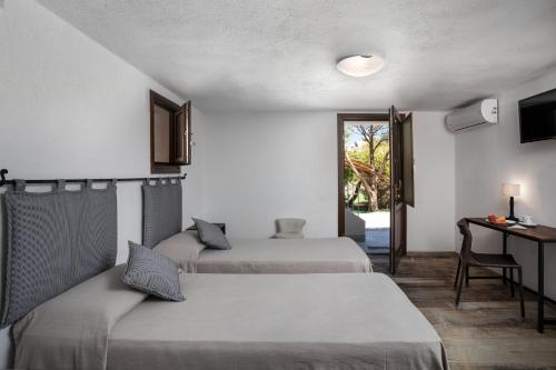 a room with two beds and a desk and a window at Il Mirto in Baja Sardinia