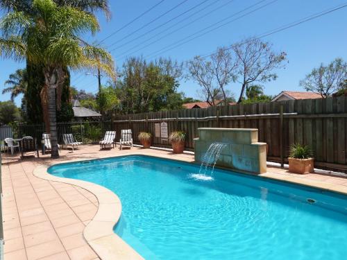 a swimming pool with a fountain in a yard at Marion Motel and Apartments in Adelaide