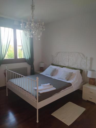 a bedroom with a white bed and a chandelier at L'appartamento Italia B. in Treviso