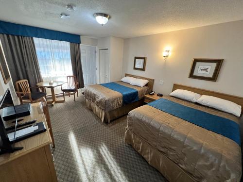 a hotel room with two beds and a table at Motel Du Chevalier in Gatineau
