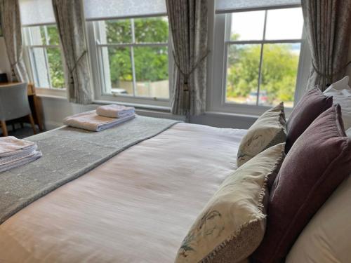 a bedroom with a large bed with pillows and windows at The Jug And Bottle in Heswall