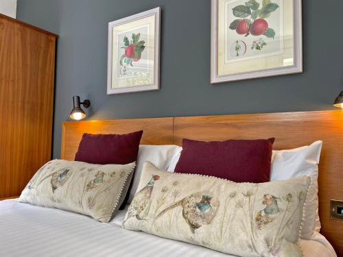 a bed with two pillows and two pictures on the wall at The Jug And Bottle in Heswall