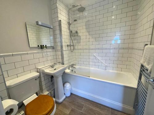 a bathroom with a tub and a toilet and a sink at The Jug And Bottle in Heswall