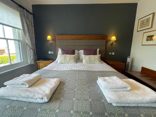 a bedroom with a large bed with two towels on it at The Jug And Bottle in Heswall