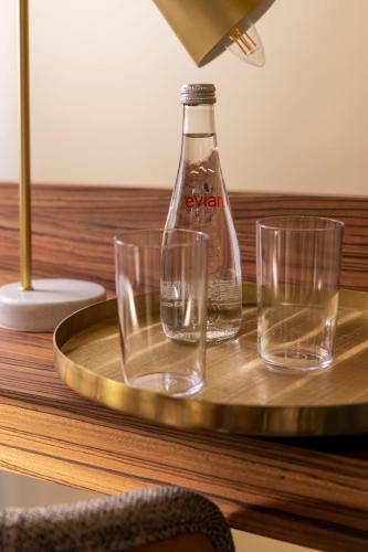 a bottle and glasses on a tray on a table at Hotel Le Rocroy in Paris