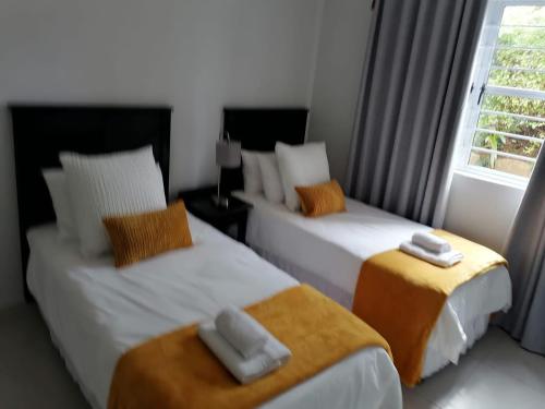a bedroom with two beds with towels on them at Caribbeans Estates Villa T13 Tortuga in Port Edward