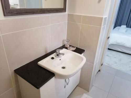 a bathroom with a white sink and a mirror at Caribbeans Estates Villa T13 Tortuga in Port Edward