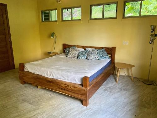 1 dormitorio con cama de madera en una habitación con ventanas en Jungle Villa copa de árbol, oceanview, infinity en Montezuma
