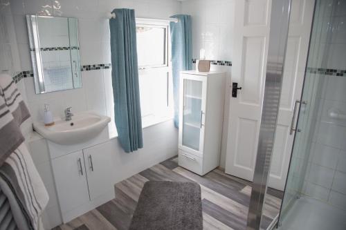 uma casa de banho com um lavatório e uma cabina de duche em vidro. em An Tigín Buí em Glanbannoo Upper