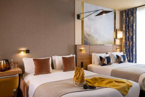 a hotel room with two beds with a yellow robe on them at Hotel Le Rocroy in Paris