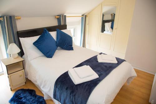 um quarto com uma grande cama branca com almofadas azuis em An Tigín Buí em Glanbannoo Upper