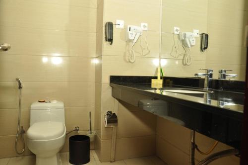 a bathroom with a toilet and a sink and a phone at Harmony Hotel in Addis Ababa